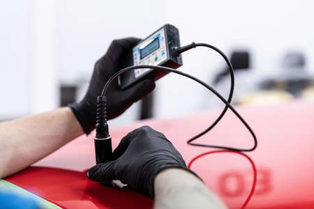 Man car detailing studio worker checking varnish thicknessの写真素材