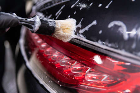 Car detailing studio worker cleaning car with brush