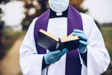 Young Catholic priest reading bible on a country road.の写真素材