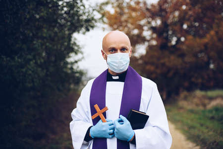 Man priest in a protective mask and protective gloves during a pastoral visit.の写真素材
