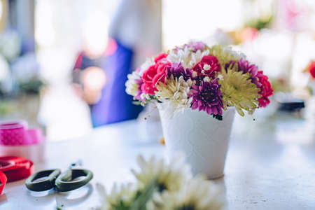 Beautiful multi-colored bouquet different fresh cut flowers in white flower pot in a flower shop.の写真素材