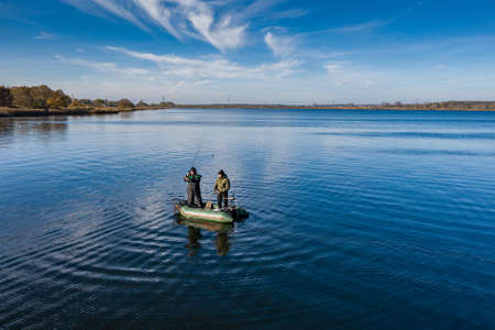 The men in the middle of the lake are fishing on a beautiful autumn day.の写真素材