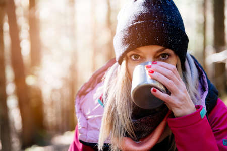 A tourist drinks hot tea on a mountain trail on a cold day.の写真素材