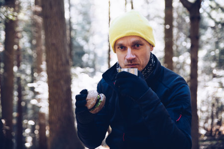Man traveller drinking from his mug of hot coffee or tea the during wonderful mountain trip.の写真素材
