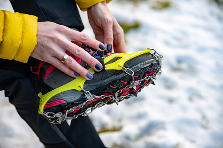 Mountain climber (girl with a manicure) puts on crampon.