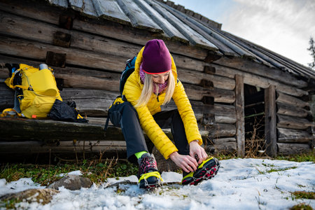 Beautiful female tourist in an alpine resort wears crampons before climbing the top.の写真素材