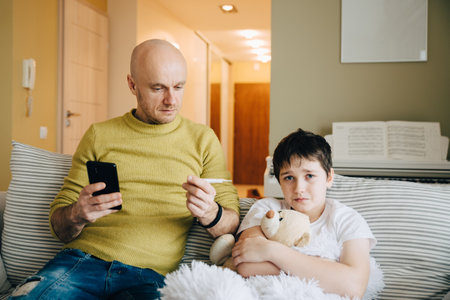 The single father measures the temperature his sick son.の写真素材