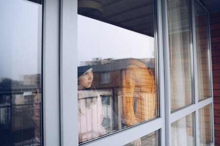 Sad children are looking out the window. Time of the pandemic.の写真素材