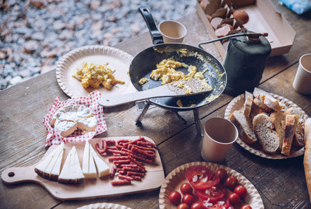 Delicious tourist breakfast on the camping. Frying scrambled eggs outdoors.の写真素材