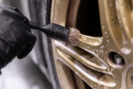 Car wash worker cleaning sports car wheel with a special brushの写真素材
