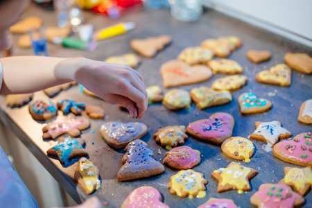 Girl decorating gingerbread cookies at homeの写真素材