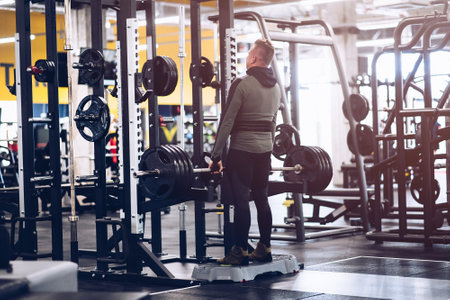 The man in the gym is lifting weights.