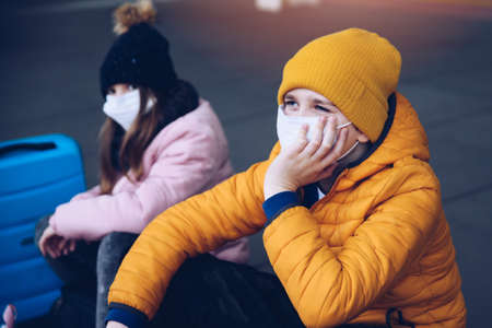 Children wearing protective masks at a train station during a pandemic.の写真素材