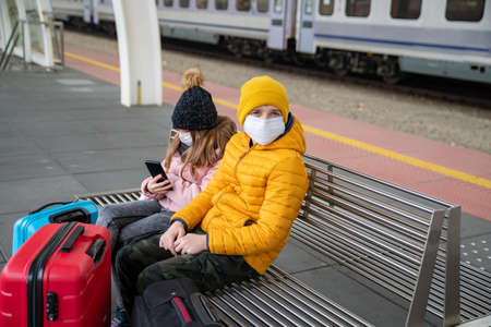 Children wait for a train at a train station during a pandemic.の写真素材