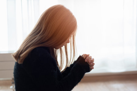 Young girl with long hair focused on praying at home.の写真素材