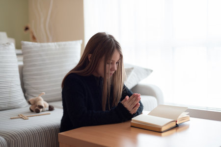 The long-haired girl prays intently in her home.