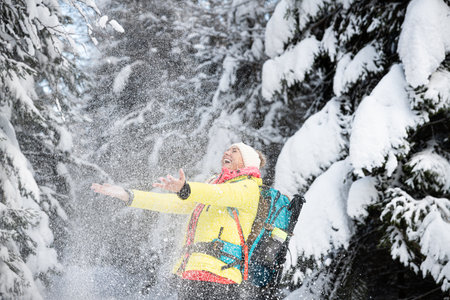 A beautiful, smiling tourist is pouring snow. Lovely winter scenery.の写真素材