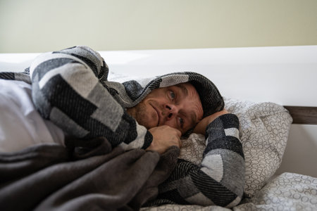 Depressed man lying in his bed and feeling bad.の写真素材