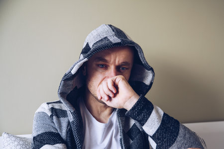Depressed man sitting on bed in bedroom.の写真素材
