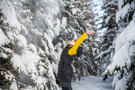 Happy woman is throwing snow on a beautiful winter day.の写真素材
