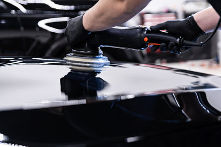 Car detailing studio worker polishing car paint