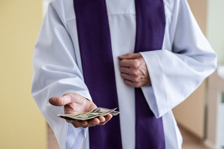 Catholic cleric priest counting american money dollar.の写真素材