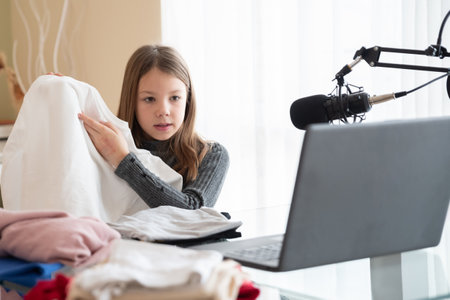 A young vlogger shows clothes online while sitting at home.の写真素材