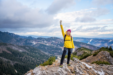 Hiker woman standing with hands up achieving the top.
