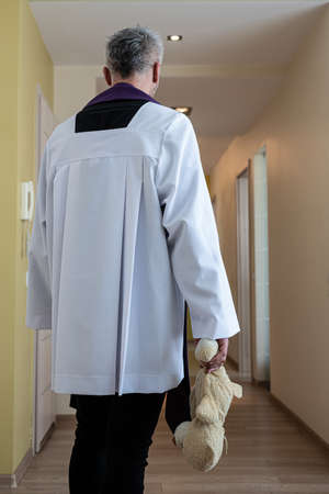 Priest holding child plush toy teddy bear