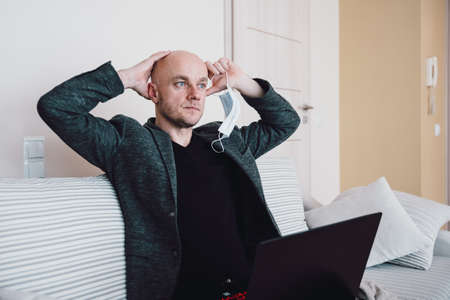 Male businessman sitting on the sofa and grabs his head from daybreak. Stock market crash.の写真素材