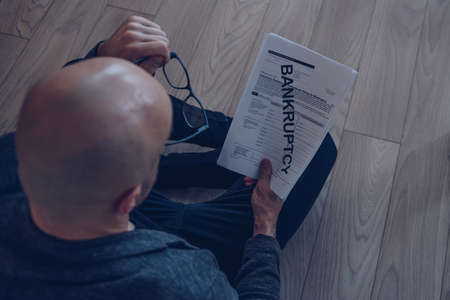 The man went bankrupt. He holds a bankruptcy petition in his hand.の写真素材