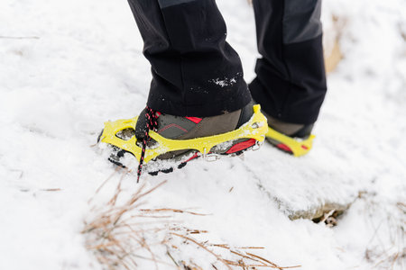 Woman hiking in the snowy mountains. Crampons on shoes.