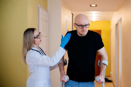 Physical, doctor, nurse therapist helping patient in rehabilitation in his house..