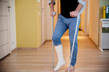 Disabled young man using crutches to walk.