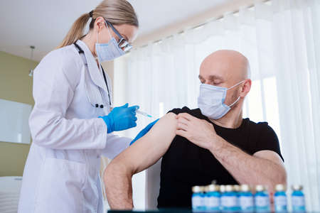 Doctor injecting vaccine into patient arm. Covid-19 or Coronavirus vaccine.の写真素材
