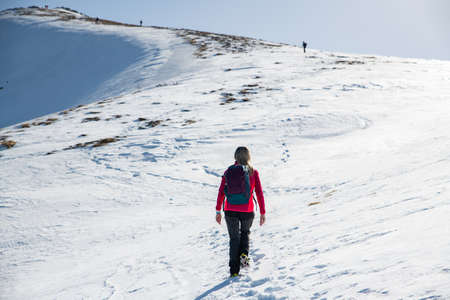 Female tourist in red jacket and backpack goes to the top.