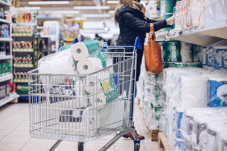 Woman shopping at supermarket choosing toilet paper.の写真素材