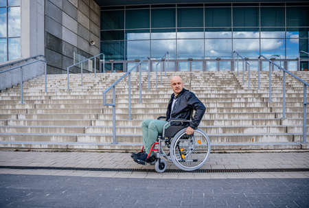 Disabled man on wheelchair in front of stairs.の写真素材