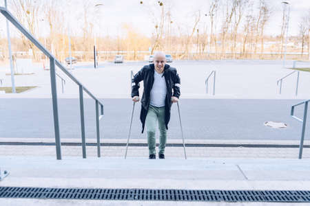 Smiling man goes up the stairswith crutches.の写真素材