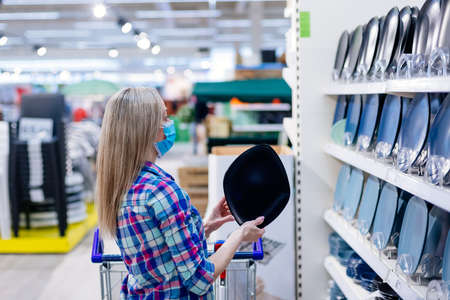 Woman in medical mask choosing dinner utensil plate in supermarket.の写真素材