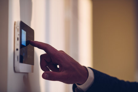 Hand and finger is pressing the alarm code on home alarm keypad.