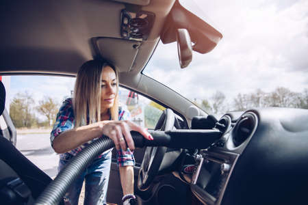 Woman cleaning interior of car with vacuum cleaner.の写真素材