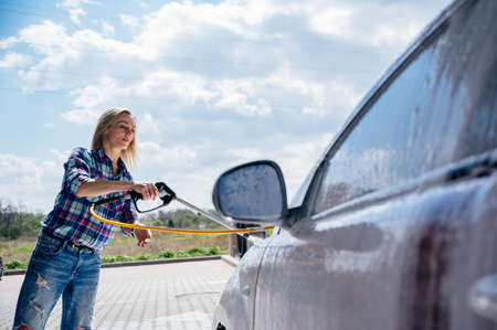 Beauty woman washing her red car at car wash.の写真素材