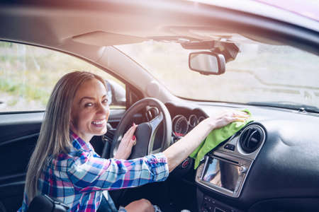 Smiling woman uses microfiber cloth with cleaning inside car.の写真素材