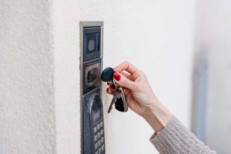 A female hand uses a remote control for a home alarm.