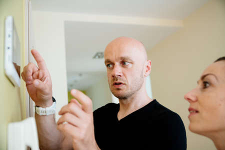 Handsome male alarm fitter mounts the alarm. Protection against burglars.の写真素材