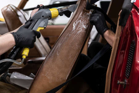 Car detailing studio workers washing car interior upholstery