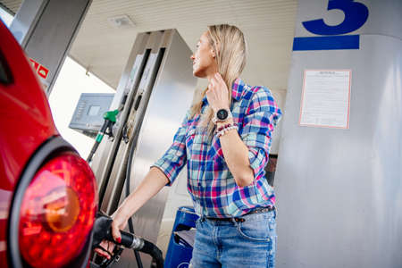 Pretty blonde woman refuel your red car.の写真素材