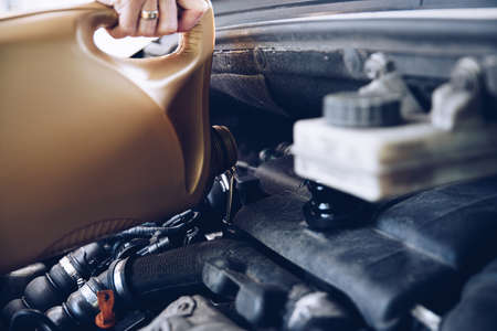 Pouring oil into the car engine. Close up of a womans hand.の写真素材