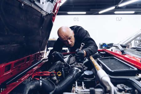 Man car service worker fixing or regulating engine